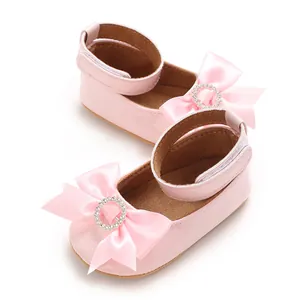 Détail de chaussures de princesse roses pour bébé avec nœuds en soie et strass étincelants
