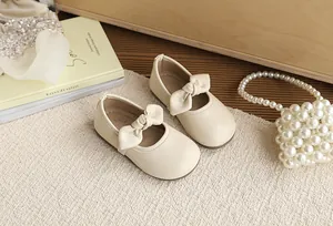 Detailed view of beige girls' Mary Jane shoes with cute bow detail on a textured mat.