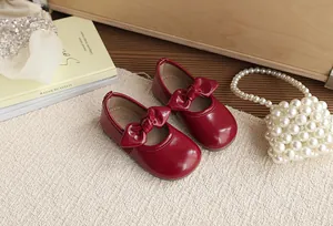 Detailed top-down view of red patent leather girl's princess shoes with a bow decoration