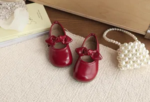 Red patent leather girls' Mary Jane shoes with elegant bow detailing for kids.