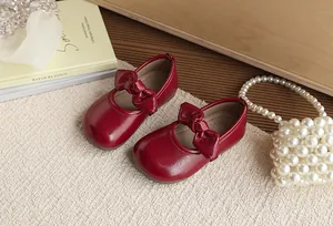 Close-up detail of stylish red girls' princess shoes featuring a large bow design