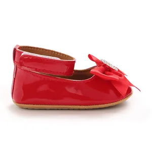Gros plan d'une chaussure de princesse rouge pour bébé avec nœud élégant et strass brillants