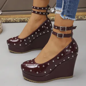 Detalle de zapatos de cuña en charol granate con tachuelas plateadas y doble correa al tobillo.