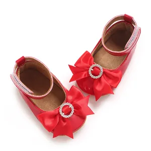 Vue détaillée des chaussures de princesse rouges avec nœud en satin et boucle en strass