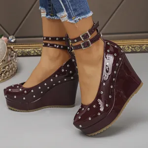 Primer plano de zapatos de cuña Mary Jane de charol granate con remaches plateados