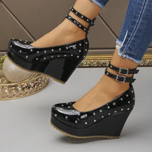 Primer plano de zapatos Mary Jane negros con cuña, tachuelas y tiras al tobillo