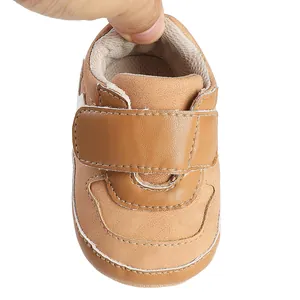 Detail view of brown faux leather baby sneaker with adjustable hook and loop strap.