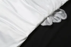 Makrodetail eines weißen Faltenstoffs mit eleganter floraler Patchwork-Applikation