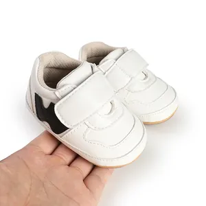 Handheld close-up of white infant sneakers with velcro straps for baby walking.