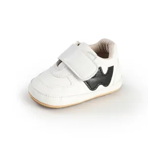 Side view of white baby sneakers with Velcro strap and black W design detail