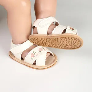 Detailed view of white baby sandals with floral embroidery and non-slip rubber sole