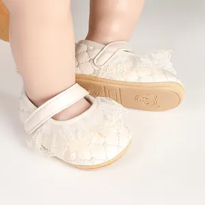 Detail of cream lace baby princess shoes with quilted texture and soft rubber soles.