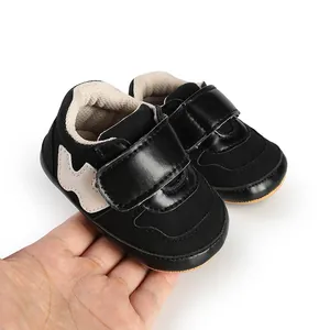 Close-up of black baby pre-walker sneakers with hook and loop straps on white background
