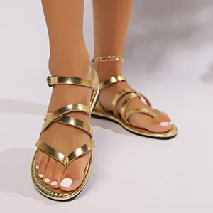 Macro view of gold metallic multi-strap flat sandals with adjustable buckle.