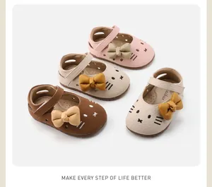 Close-up of adorable baby girl cat-themed walking shoes with bows in pink and beige