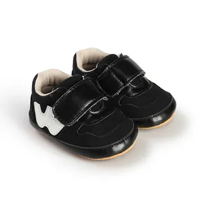 Detailed side view of black baby boy sneakers with velcro straps and white W pattern