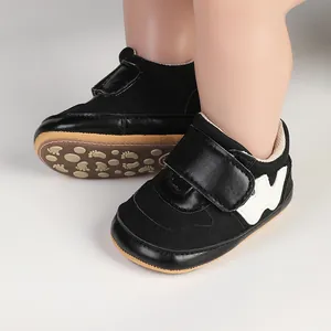 Detail view of black infant pre-walker sports shoes with white W logo and textured rubber sole.
