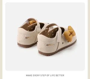 Rear view of cream-colored baby walking shoes featuring a yellow bow and cat ear details.