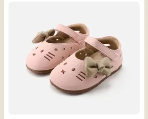 Close-up detail of pink baby girl walking shoes featuring cat embroidery and green bows.