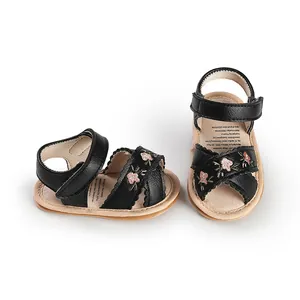 Detail of black baby walking sandals with pink floral embroidery and velcro straps