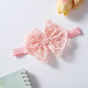 Close-up of delicate pink lace bow baby headband with elegant pearl center ornament