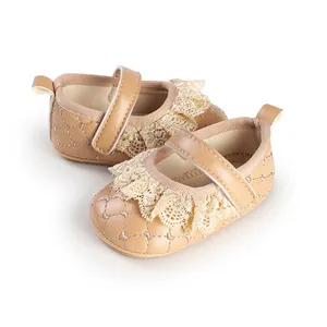 Close-up of beige infant girl shoes with delicate lace trim and quilted pattern.