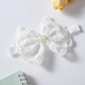 Close-up of white lace bow headband with pearls for newborn photography accessories.