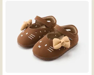Close-up of baby girl brown soft-sole shoes with cat embroidery and yellow bows
