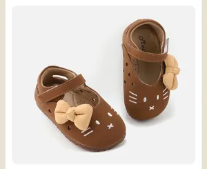 Top view of brown baby girl shoes featuring cute cat face and cream leather bow detail