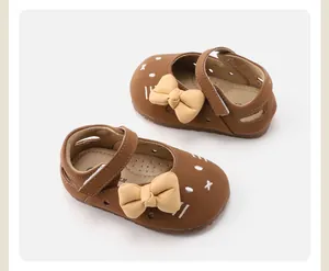 Detailed view of brown baby girl shoes with soft soles and cute beige bow accents.