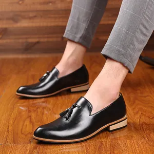 Detailed view of men's black pointed-toe leather loafers with tassels on a model