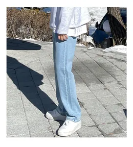 Detail view of men's summer light blue straight-leg jeans in a natural outdoor setting