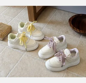 Detailed view of stylish white children's sports shoes featuring yellow and purple laces