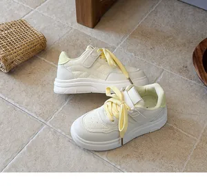 Detailed view of fashionable children's white sneakers with soft yellow laces on tiled floor