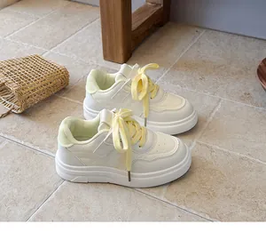 Side view detail of stylish children's white sneakers featuring bright yellow laces.