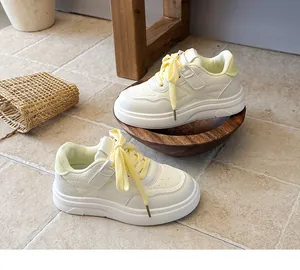 Detail view of stylish cream and pale yellow children sneakers on neutral tiled floor