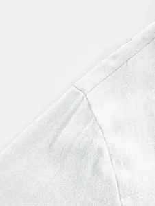 Close-up detail of the shoulder seam and texture on a white cotton linen shirt