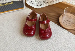 Gros plan de chaussures de princesse en cuir verni bordeaux pour fille avec nœud