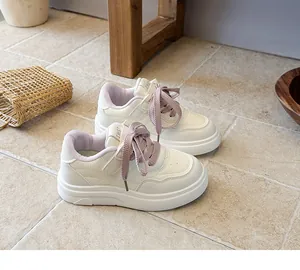 Detailed view of children's white sneakers with purple laces on stone floor