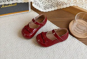 Gros plan sur les chaussures Mary Jane rétro en cuir verni rouge avec nœud pour fille
