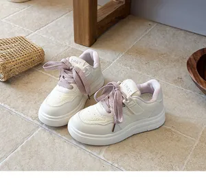 Close-up of children's white sneakers with textured pink laces and soft lining
