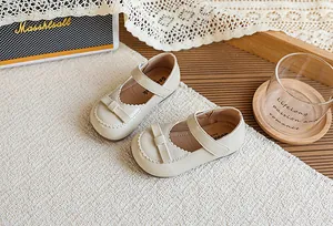 Gros plan de chaussures Mary Jane beiges pour filles avec nœud et bordure festonnée