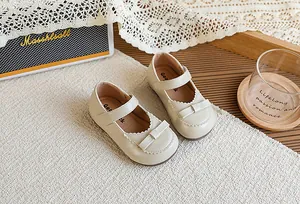 Détail de chaussures Mary Jane vintage crème pour filles avec nœud et bordure festonnée.