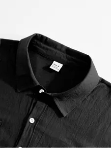 Close-up of black linen shirt collar showing material label and fabric texture.