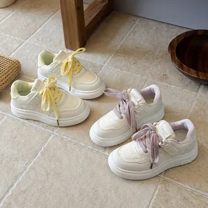 Stylish white children's sneakers for girls featuring colorful yellow and purple laces.
