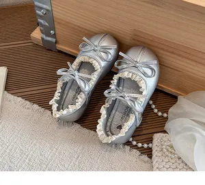 Draufsicht auf silberne Mädchen Mary Janes mit Spitzenbesatz und eleganten Doppelschleifen