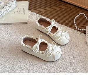Elegante cremefarbene Mädchen Mary Janes mit Spitzenrüschen und Doppelschleife.