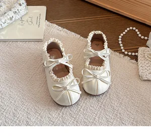 Nahaufnahme der cremefarbenen Mary-Jane-Mädchenschuhe mit Rüschen und Doppelbogen