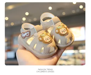 Close-up of beige toddler sandals with cute cartoon bear patches and soft soles