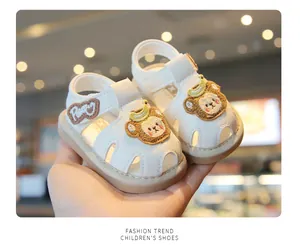 Close-up of white baby walking sandals with cute cartoon bear patch and soft sole